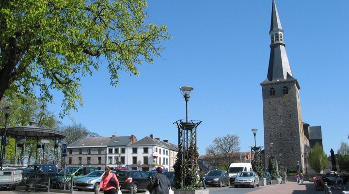 Place de Ciney avec le clocher de l'église et des voitures en stationnement