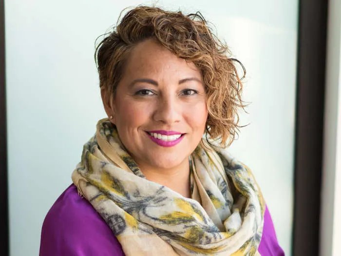 Portrait d'une femme souriante aux cheveux bouclés portant un foulard