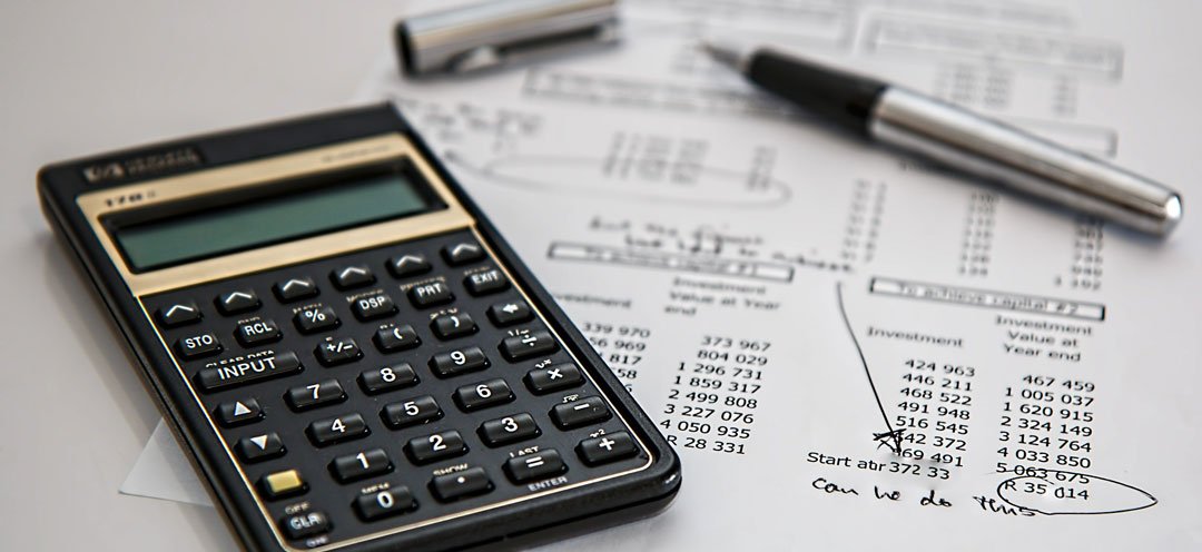 Calculatrice et stylo posés sur un tableau de chiffres imprimé