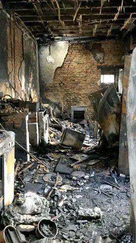 Intérieur de maison entièrement calciné, plafond effondré et débris noircis au sol