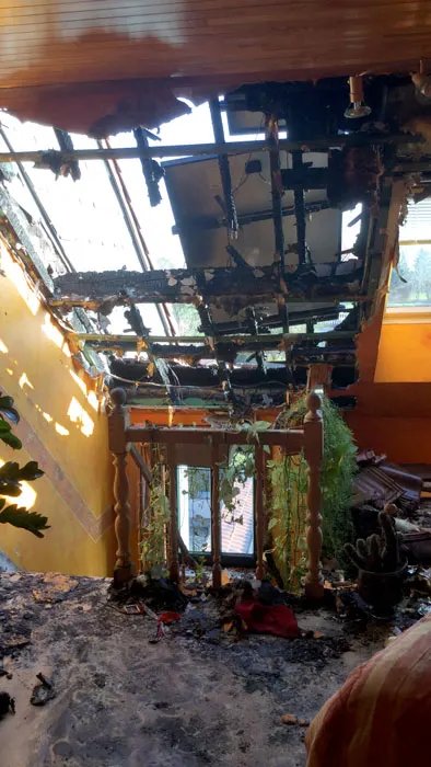 Pièce sous toiture ravagée par le feu, charpente calcinée ouverte sur le ciel